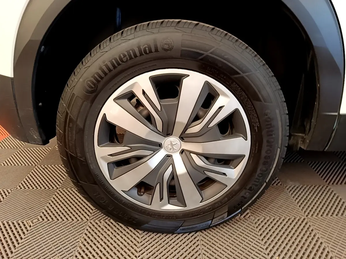 Gros plan sur la roue avant droite d’un Peugeot 2008 blanc, avec jante alliage et pneu Continental visible.
