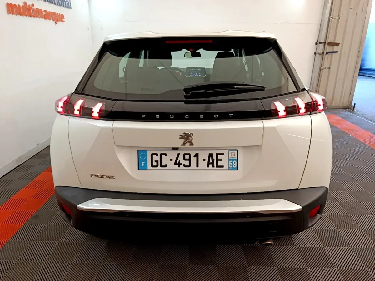 Vue arrière d'un Peugeot 2008 blanc avec feux LED allumés dans un garage fermé.