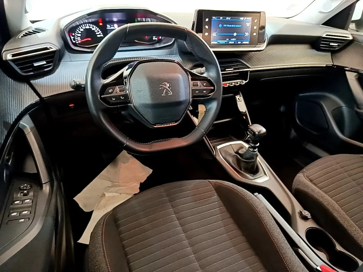 Vue intérieure avant du Peugeot 2008 1.5 BlueHDi 2021, volant cuir, écran tactile et boîte manuelle visibles.