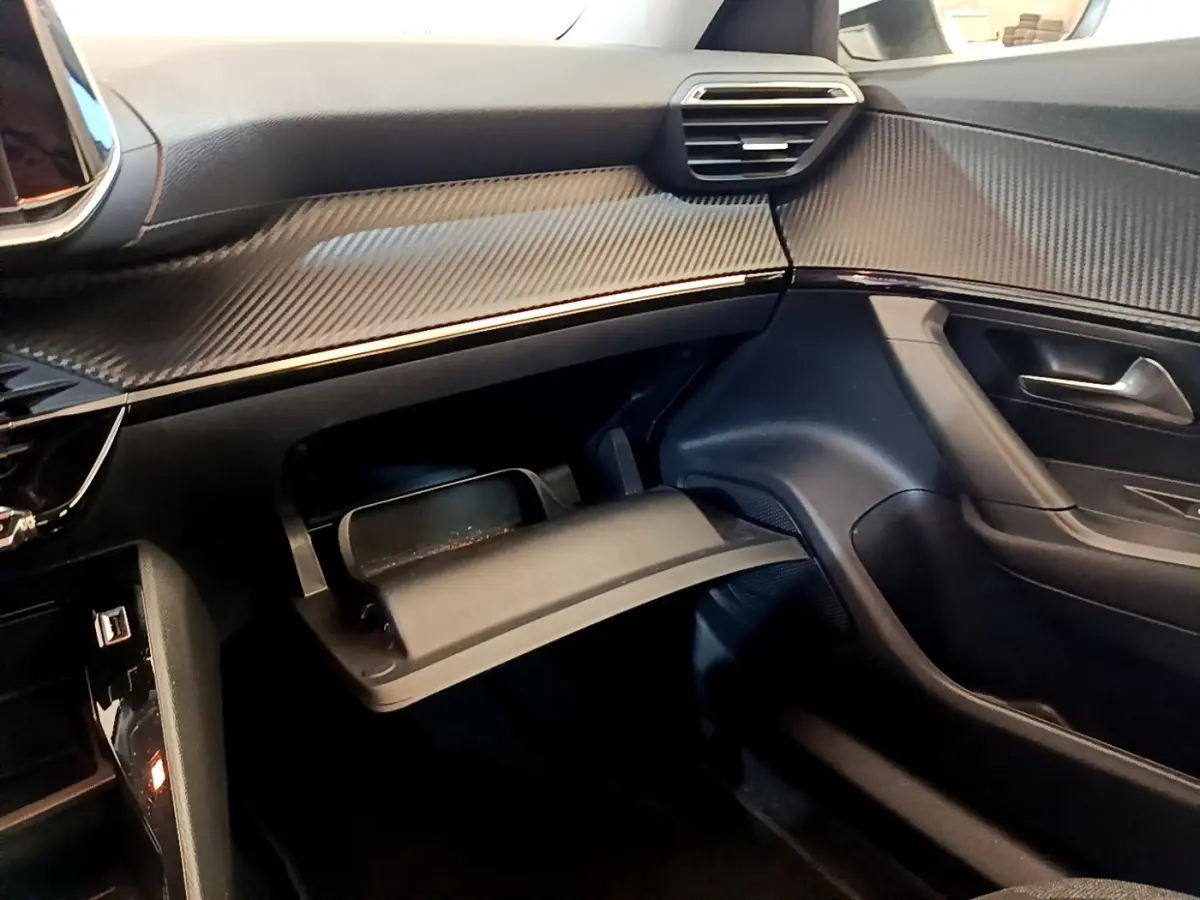 Intérieur de la Peugeot 2008 2021, vue côté passager, tableau de bord noir avec boîte à gants ouverte.