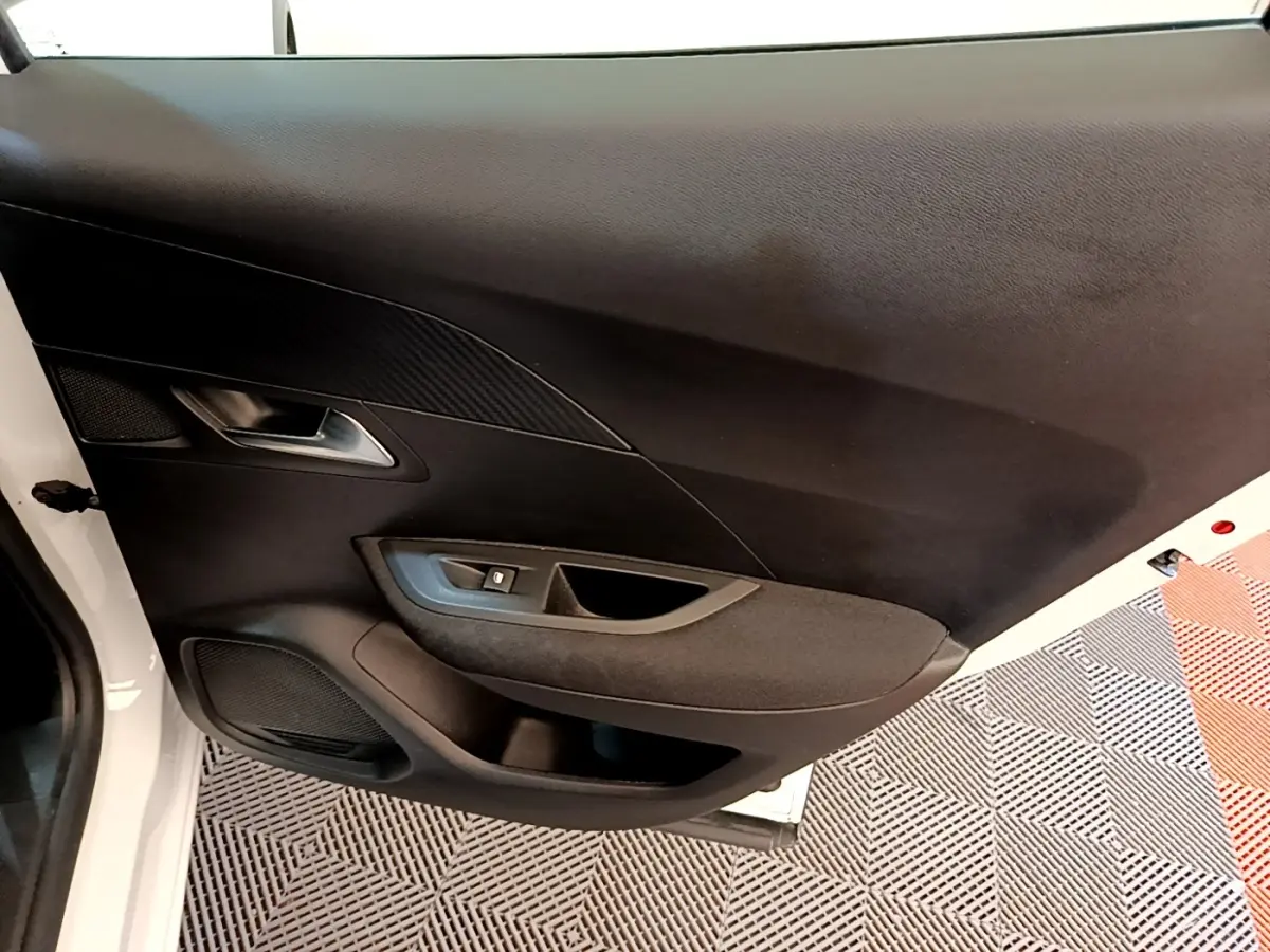 Vue intérieure de la porte avant gauche du Peugeot 2008 blanc, avec commande de lève-vitre et habillage noir.