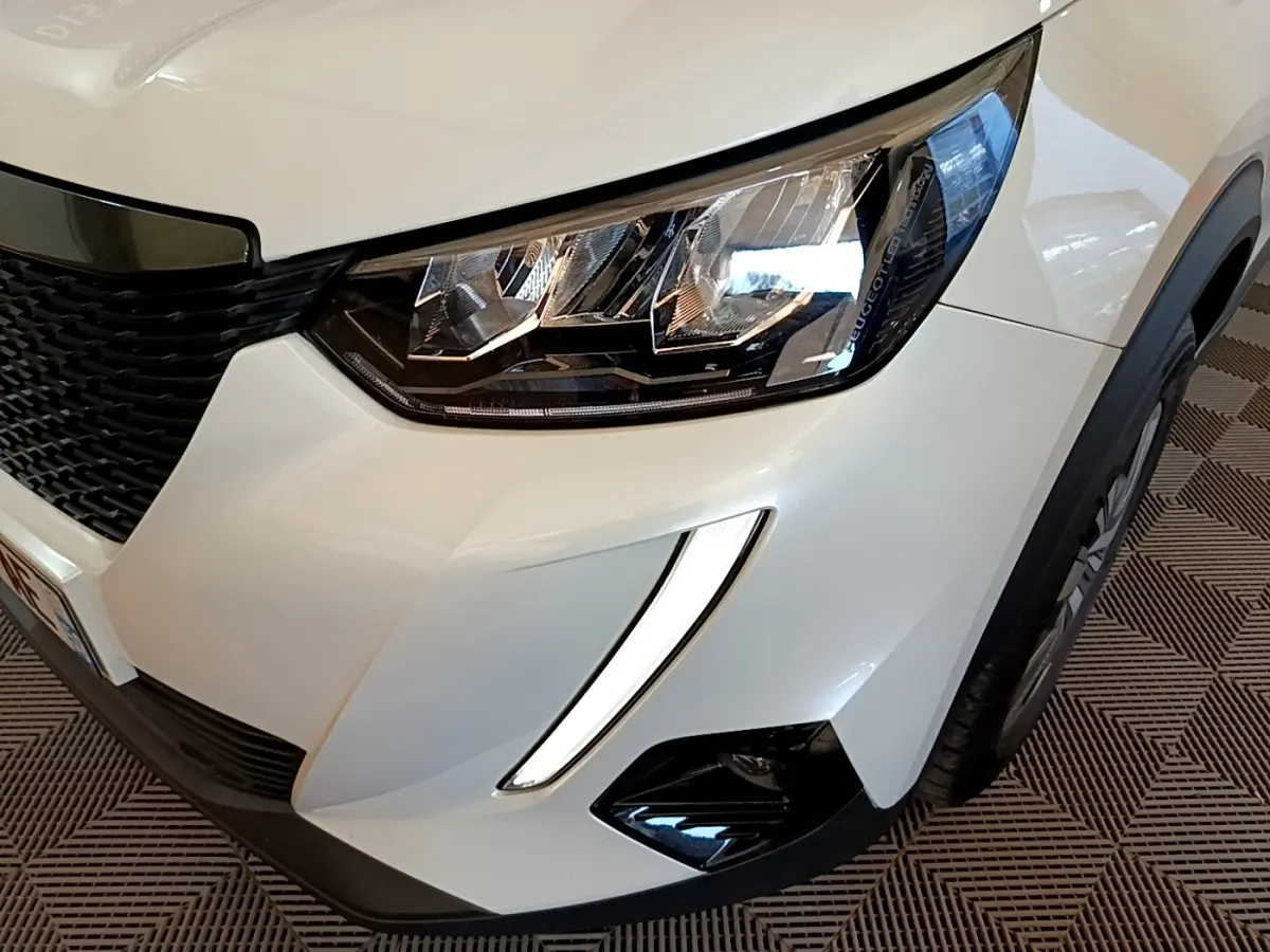 Gros plan sur l'avant droit blanc du Peugeot 2008 2021, mettant en valeur le phare LED et la grille noire.