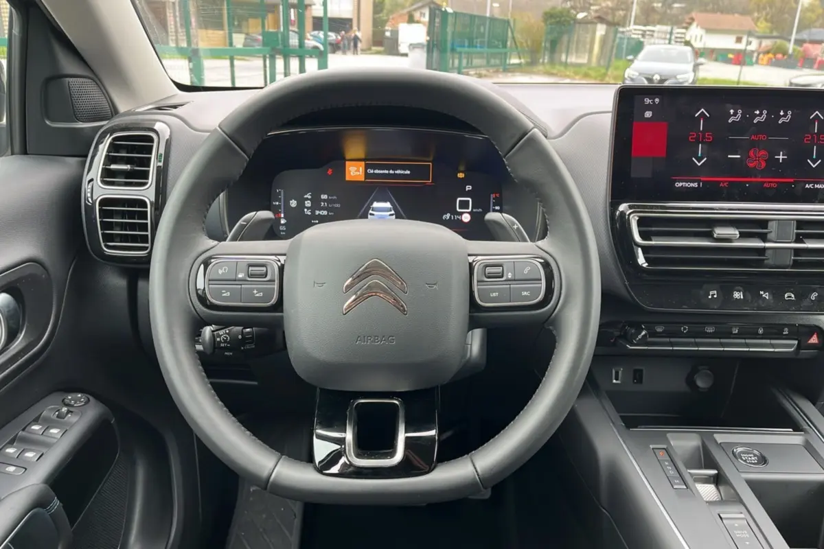 Vue frontale de l'intérieur du Citroën C5 Aircross Hybrid 145, volant cuir multifonctions et écran tactile central.