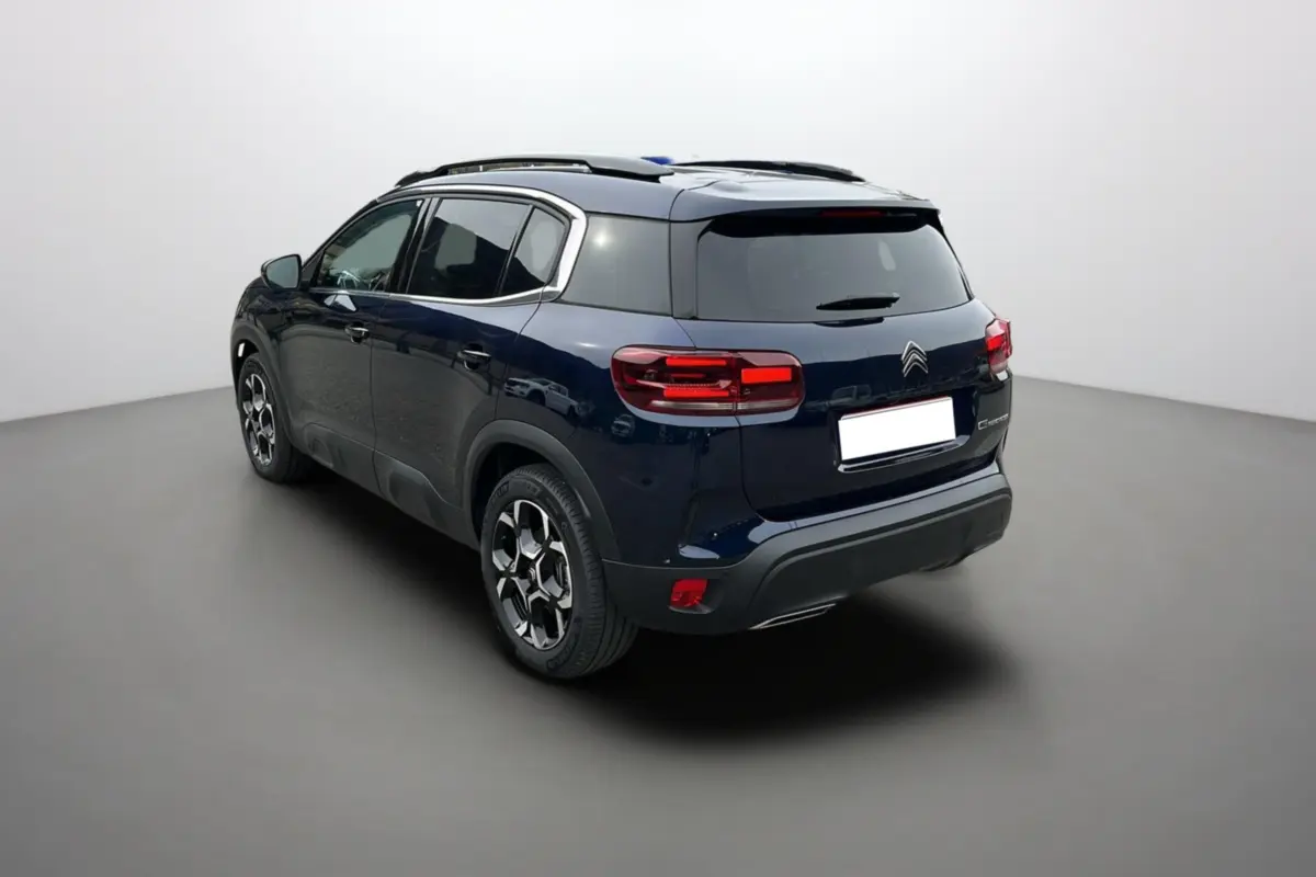 Vue 3/4 arrière droite d'un Citroën C5 Aircross Hybrid 145 Eclipse Blue avec barres de toit et jantes alu 18 pouces.
