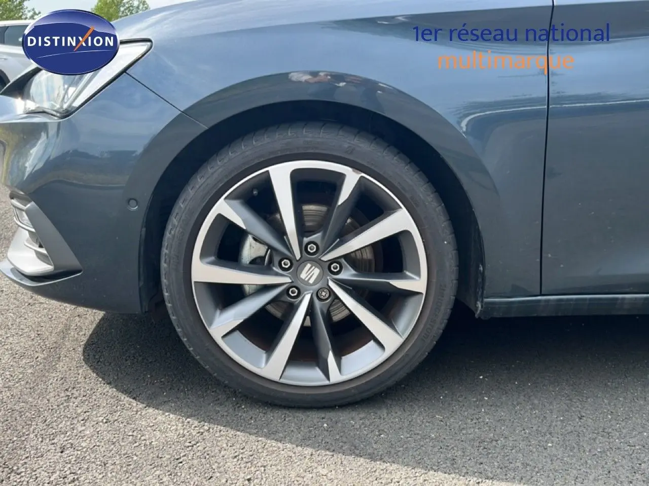 Gros plan sur la roue avant gauche d'une SEAT LEON ST gris magnétique métal, avec jante alliage à dix branches.