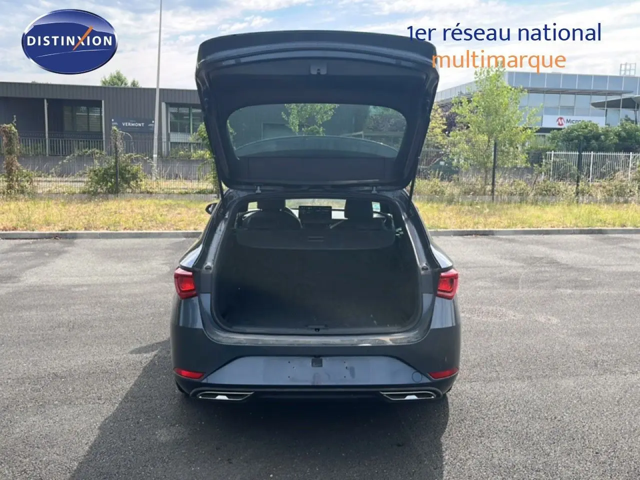 Vue arrière d’une SEAT LEON ST gris magnétique métal 2025 avec coffre ouvert sur un parking extérieur.
