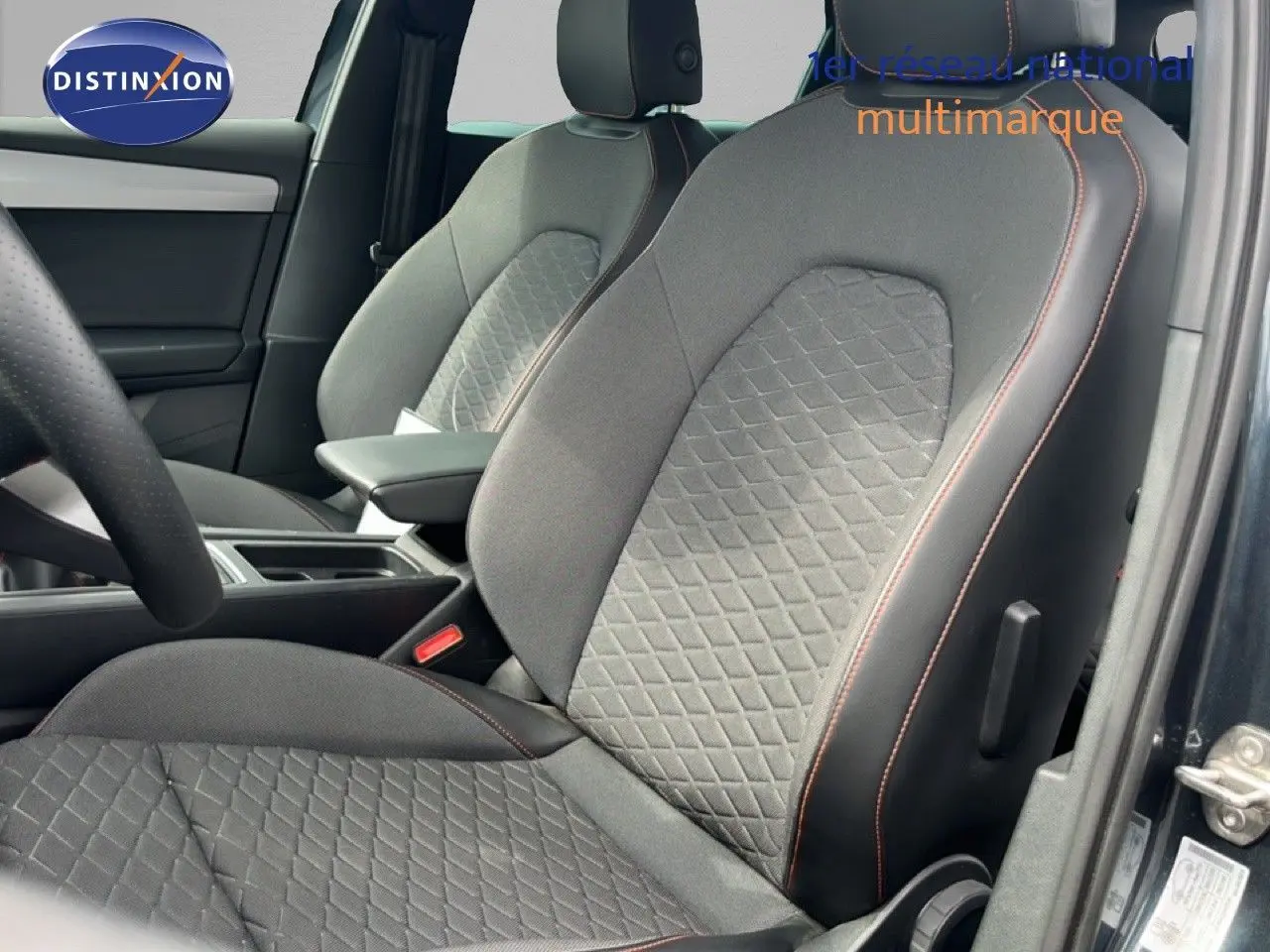 Vue intérieure rapprochée des sièges avant gris noir avec surpiqûres orange d’un SEAT LEON ST 2025 gris magnétique.