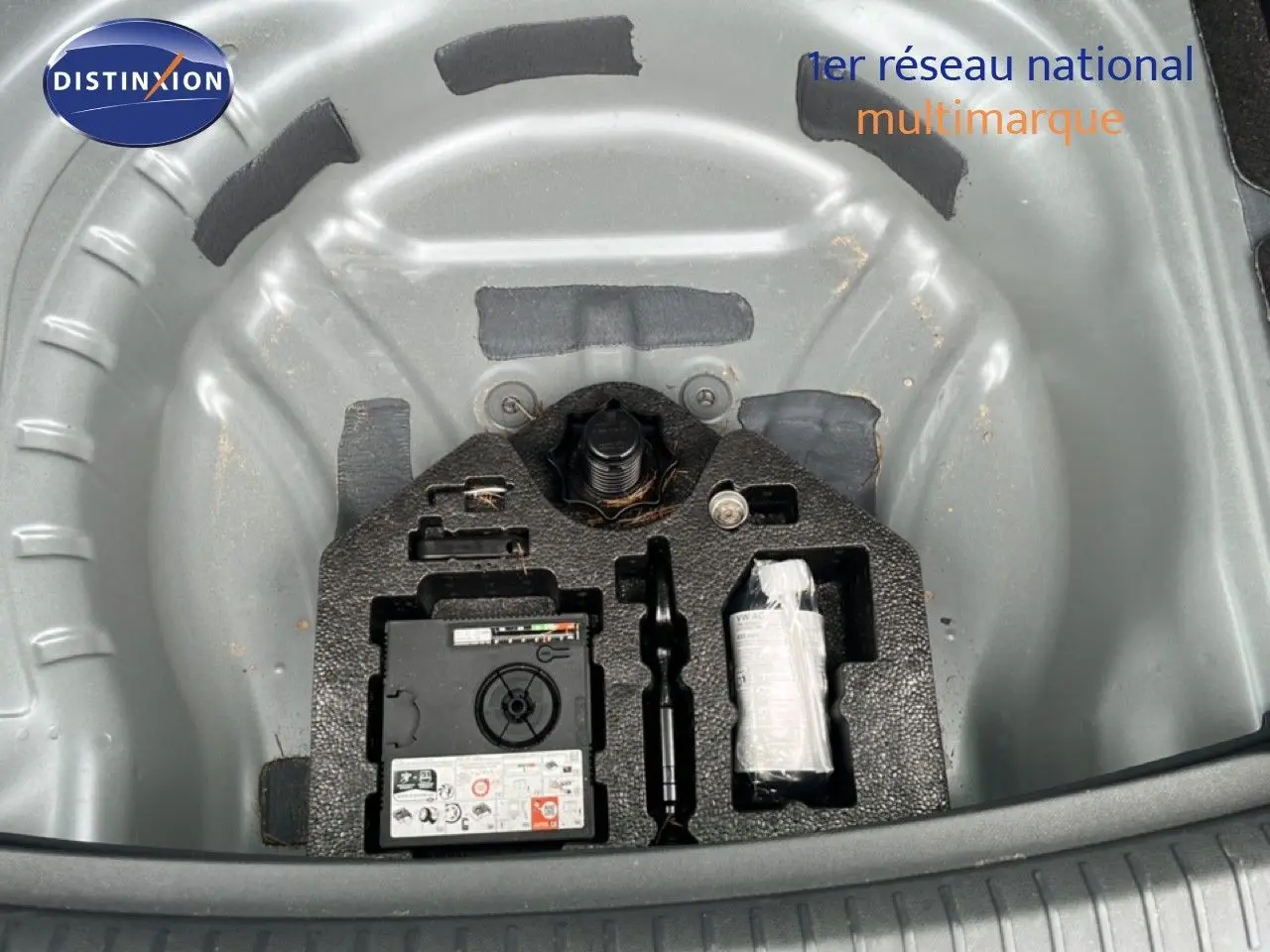 Vue plongeante sur le rangement gris métallique du kit de réparation de roue dans le coffre d'une SEAT LEON ST 2025.