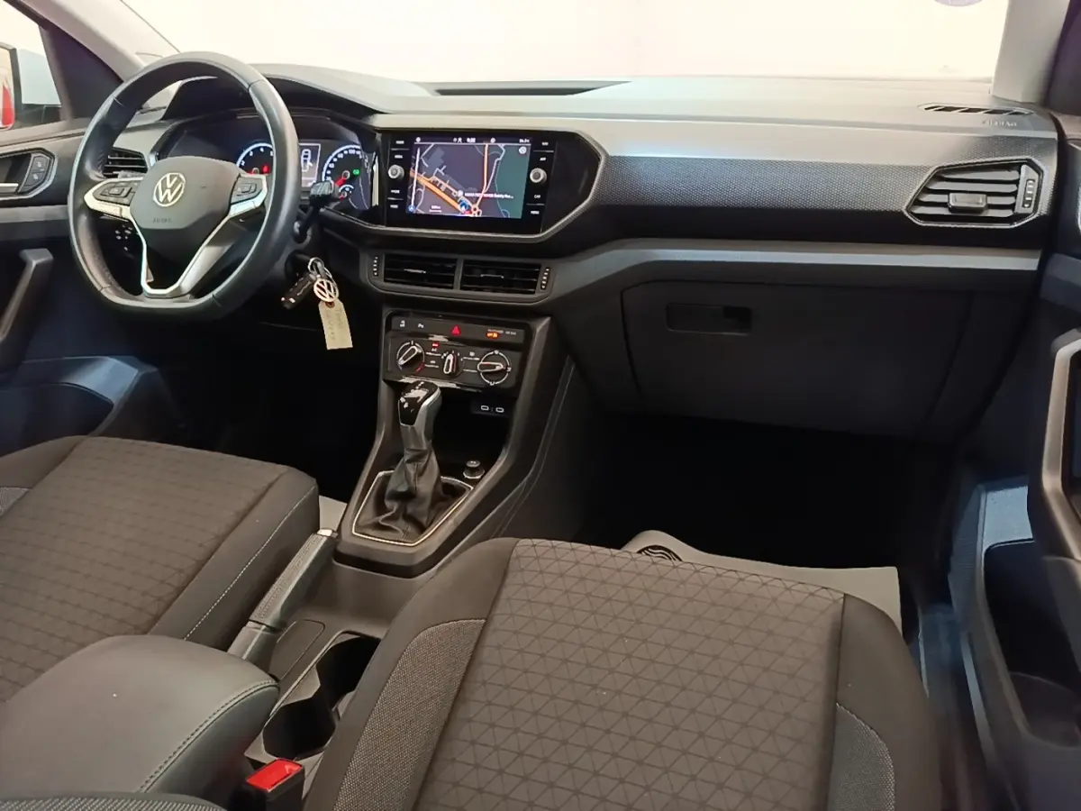 Vue intérieure avant du Volkswagen T-Cross 2022, tableau de bord noir avec écran tactile et volant multifonctions cuir.