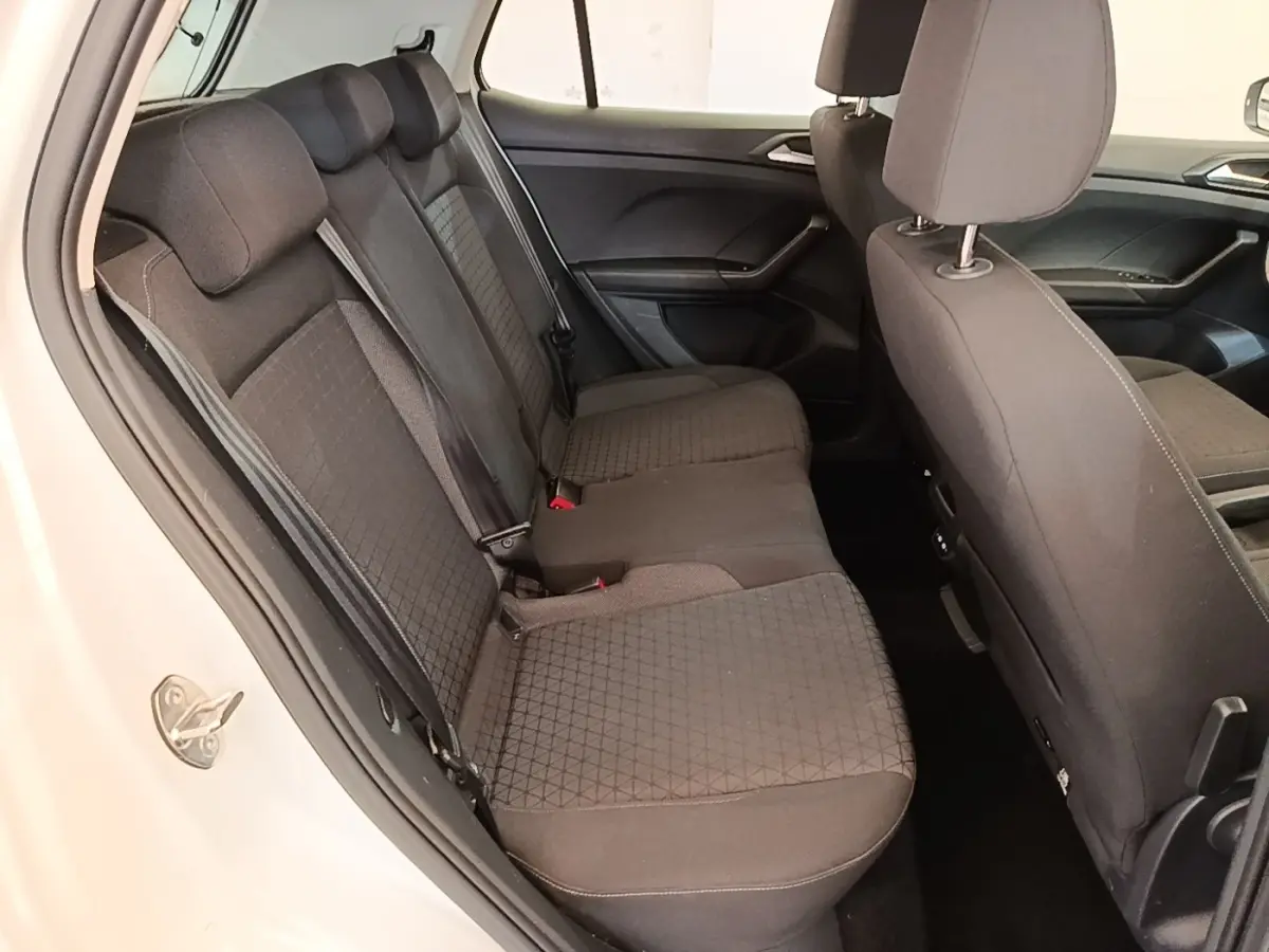 Vue intérieure côté gauche sur la banquette arrière noire du Volkswagen T-Cross blanc, avec détails des sièges et ceintures.