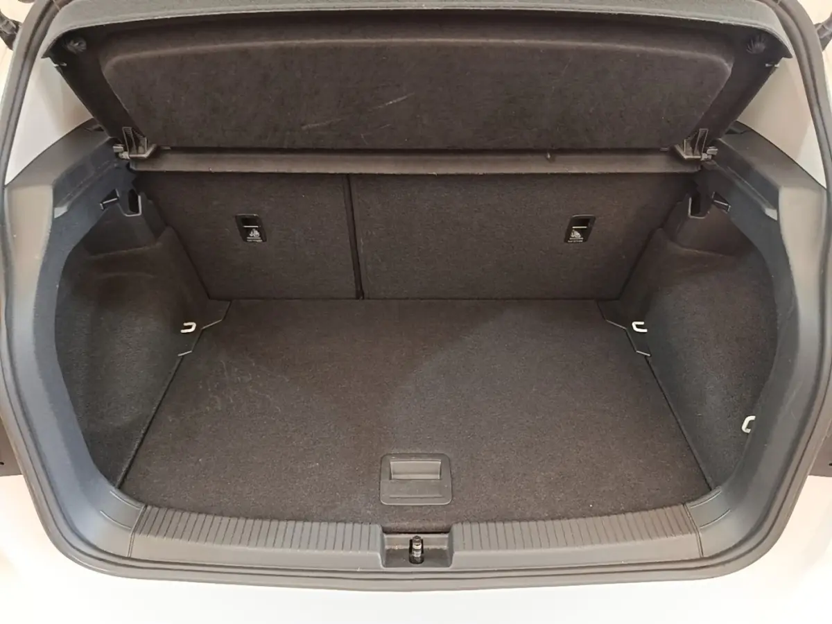 Coffre ouvert du Volkswagen T-Cross blanc, vue plongeante montrant l'espace de chargement vide et la tablette de séparation.