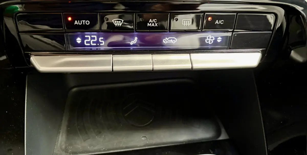 Vue rapprochée de la console centrale noire du Citroën C3 2025, affichant la climatisation et la zone de recharge sans fil.