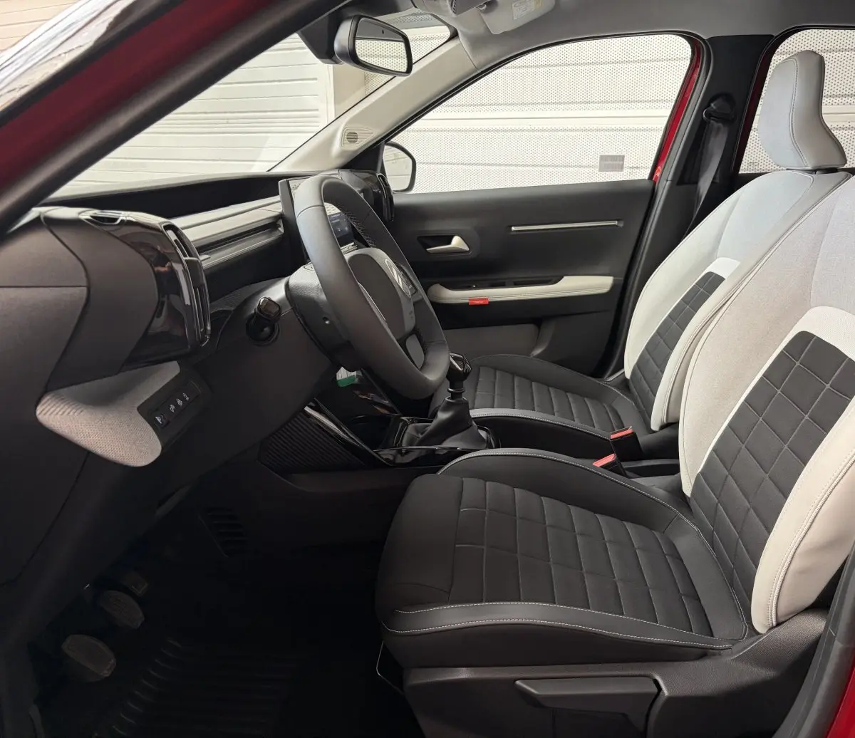Vue intérieure côté conducteur de la Citroën C3 2025, sièges bi-ton noir et beige avec volant cuir et boîte manuelle.
