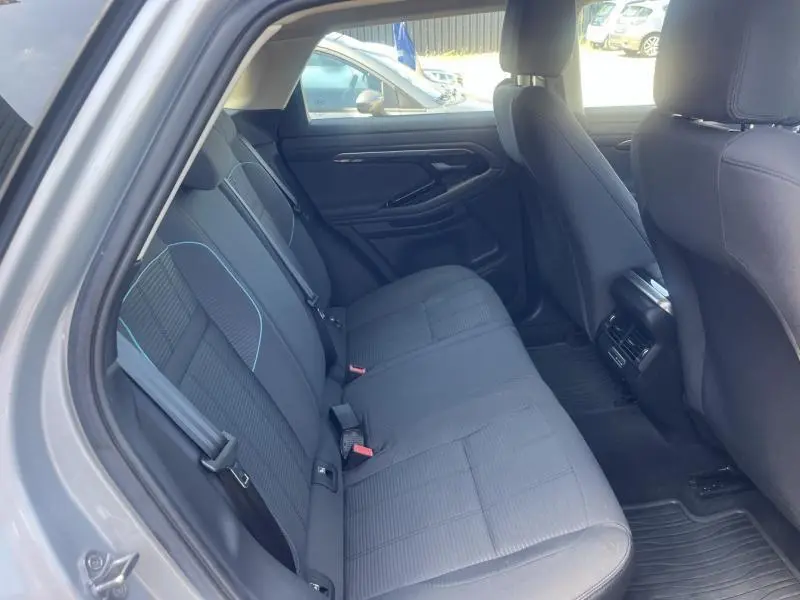 Vue intérieure arrière côté gauche du Range Rover Evoque 2019 en Indus Silver, sièges tissu noirs avec surpiqûres bleues.