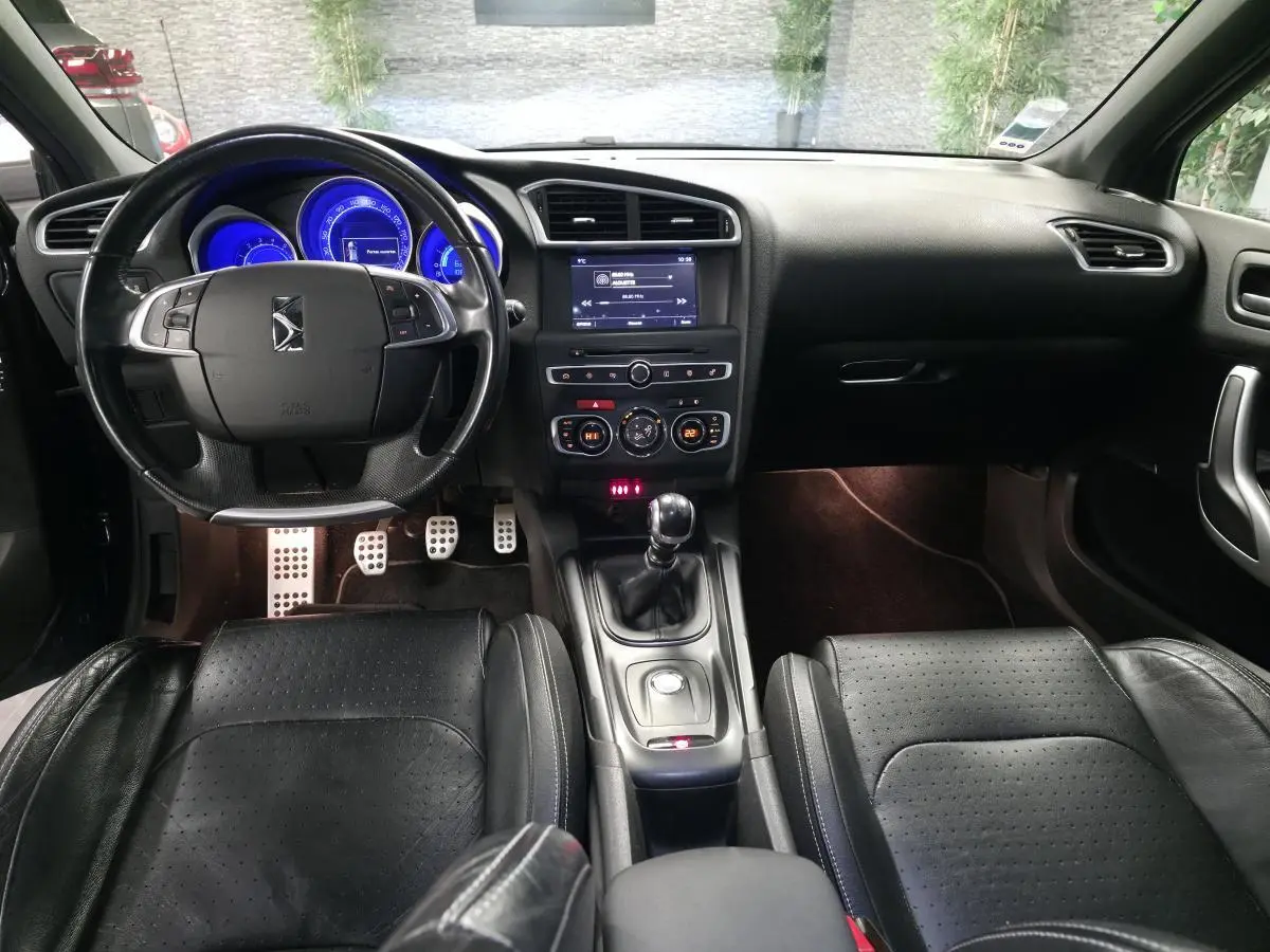 Intérieur noir cuir du DS4 2016 vu de face, avec tableau de bord éclairé en bleu et levier de vitesses manuel.