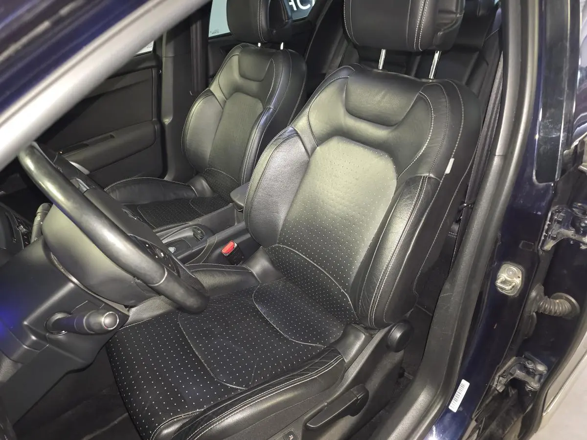 Vue intérieure côté conducteur du DS4 2016 violet montrant les sièges avant en cuir noir perforé et volant cuir.