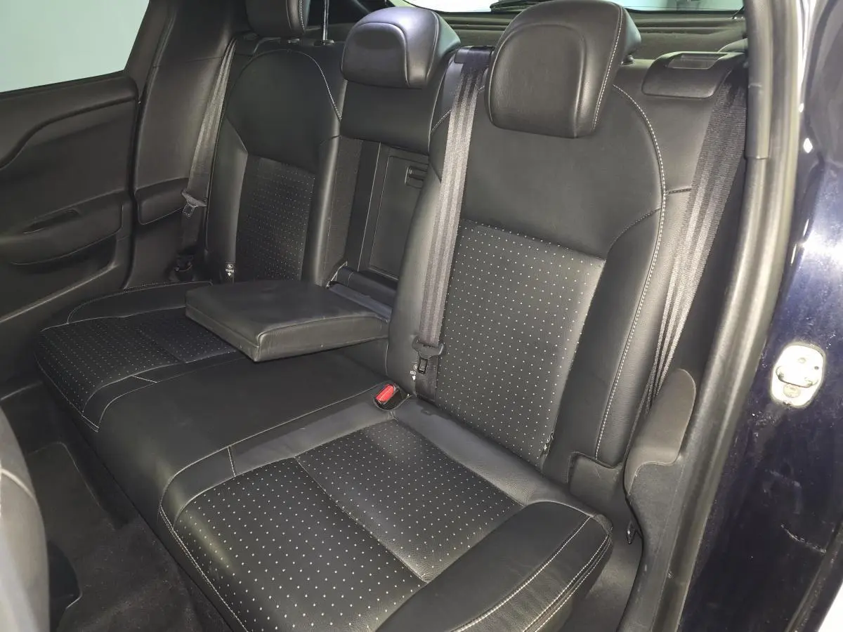 Vue intérieure sur la banquette arrière en cuir noir perforé du DS4 violet, avec accoudoir central déployé.