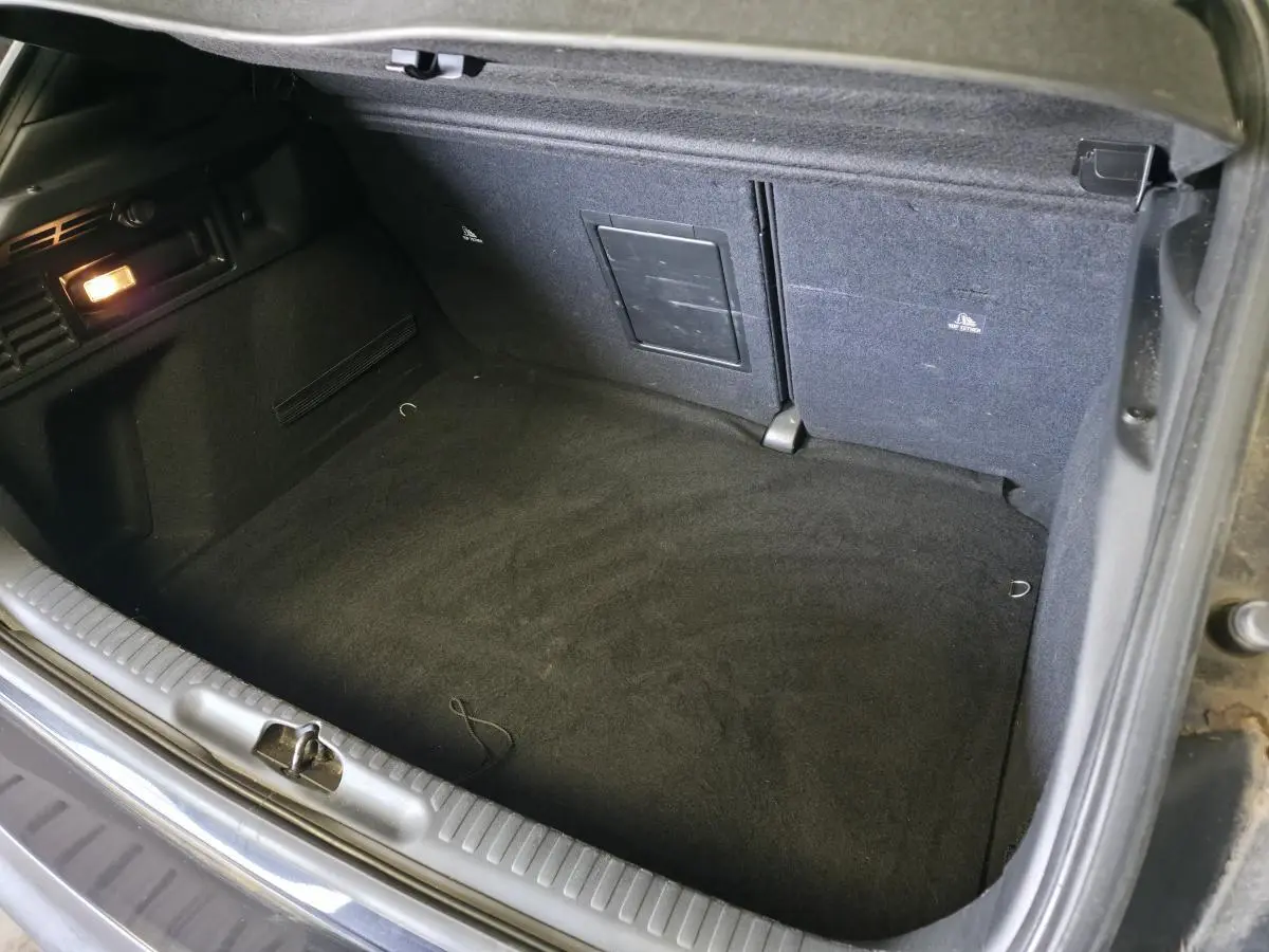 Coffre ouvert vu de dessus du DS4 violet 2016, avec tapis noir et éclairage intérieur à gauche.