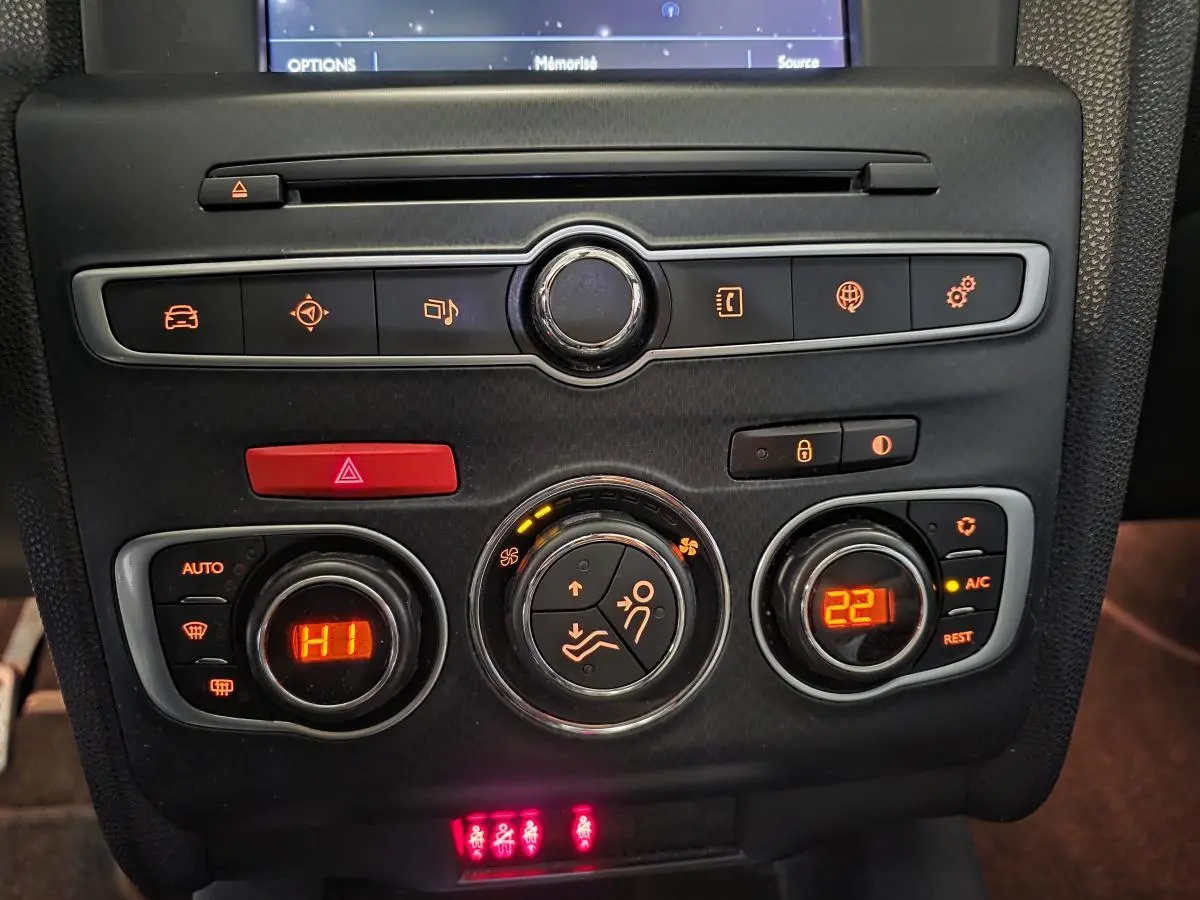 Vue rapprochée de la console centrale noire du DS4 violet, montrant les commandes de climatisation et les voyants lumineux.