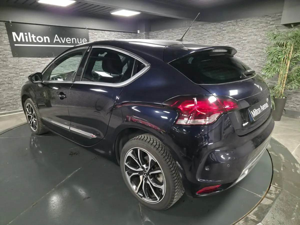 Vue 3/4 arrière droite d'une DS4 violet foncé métallisé avec jantes alliage noires et baguettes chromées.