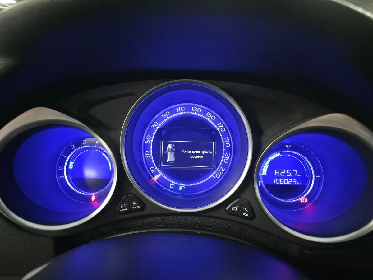 Tableau de bord du DS4 2016 avec combiné à aiguilles et affichage digital bleu, indiquant porte avant gauche ouverte.