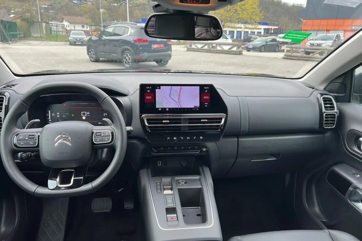 Vue intérieure avant du Citroën C5 Aircross Hybrid noir 2025, tableau de bord avec écran tactile et volant multifonctions cuir.