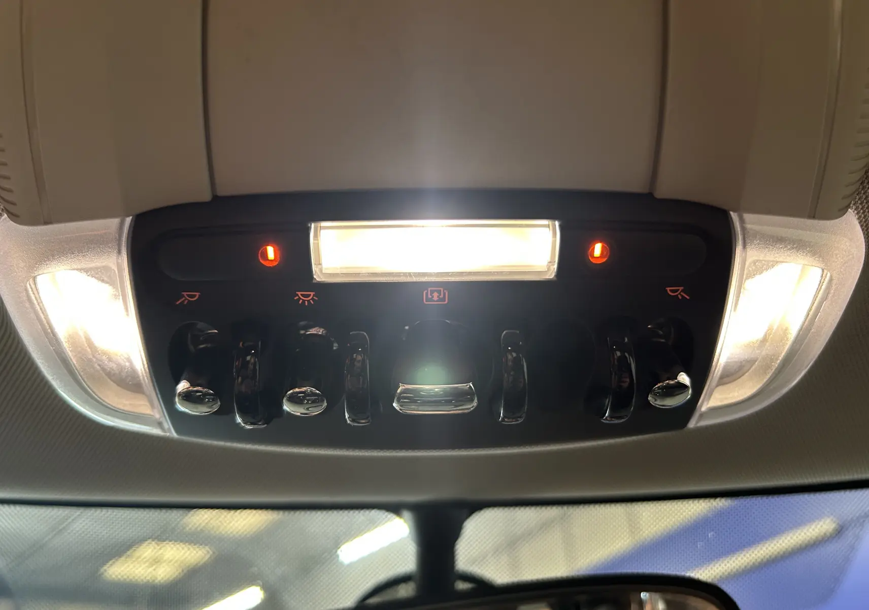 Vue intérieure du plafonnier avec commandes et éclairages allumés dans une MINI 5P Cooper D bleu de 2015.