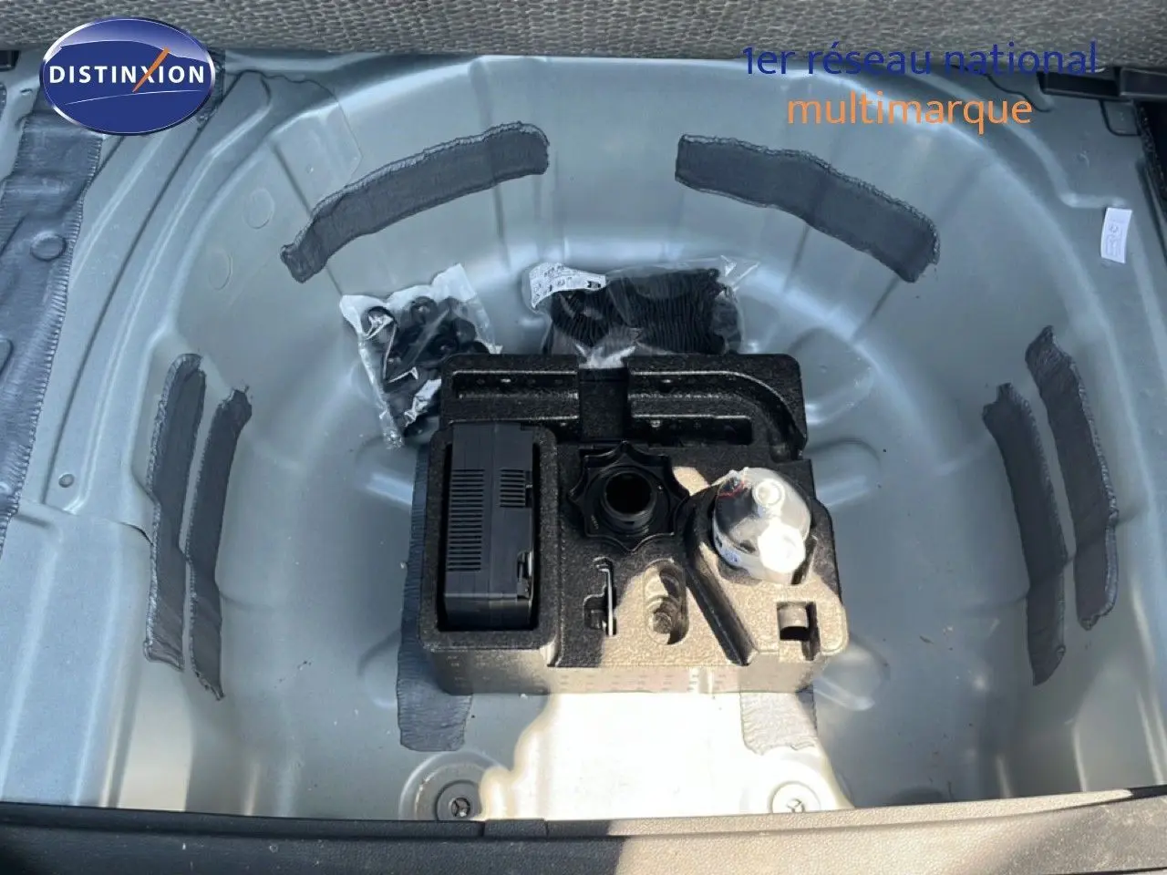 Gros plan sur le rangement de la roue de secours d'une SEAT Arona 2025, montrant les outils et accessoires dans un compartiment gris métallique.