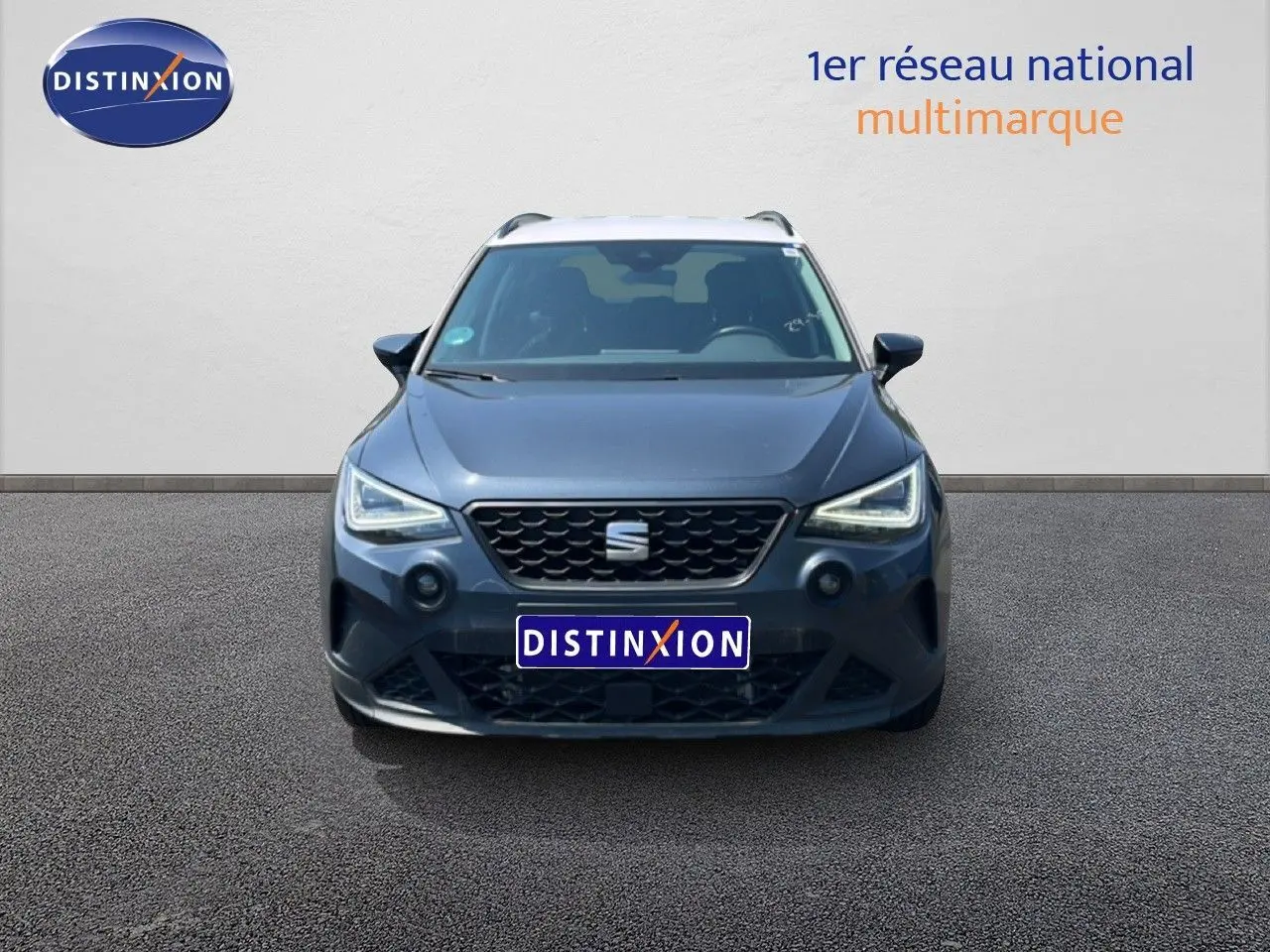 Vue frontale d'un SEAT Arona gris Magnetic Metal avec toit blanc, affichant ses phares LED allumés et calandre noire.