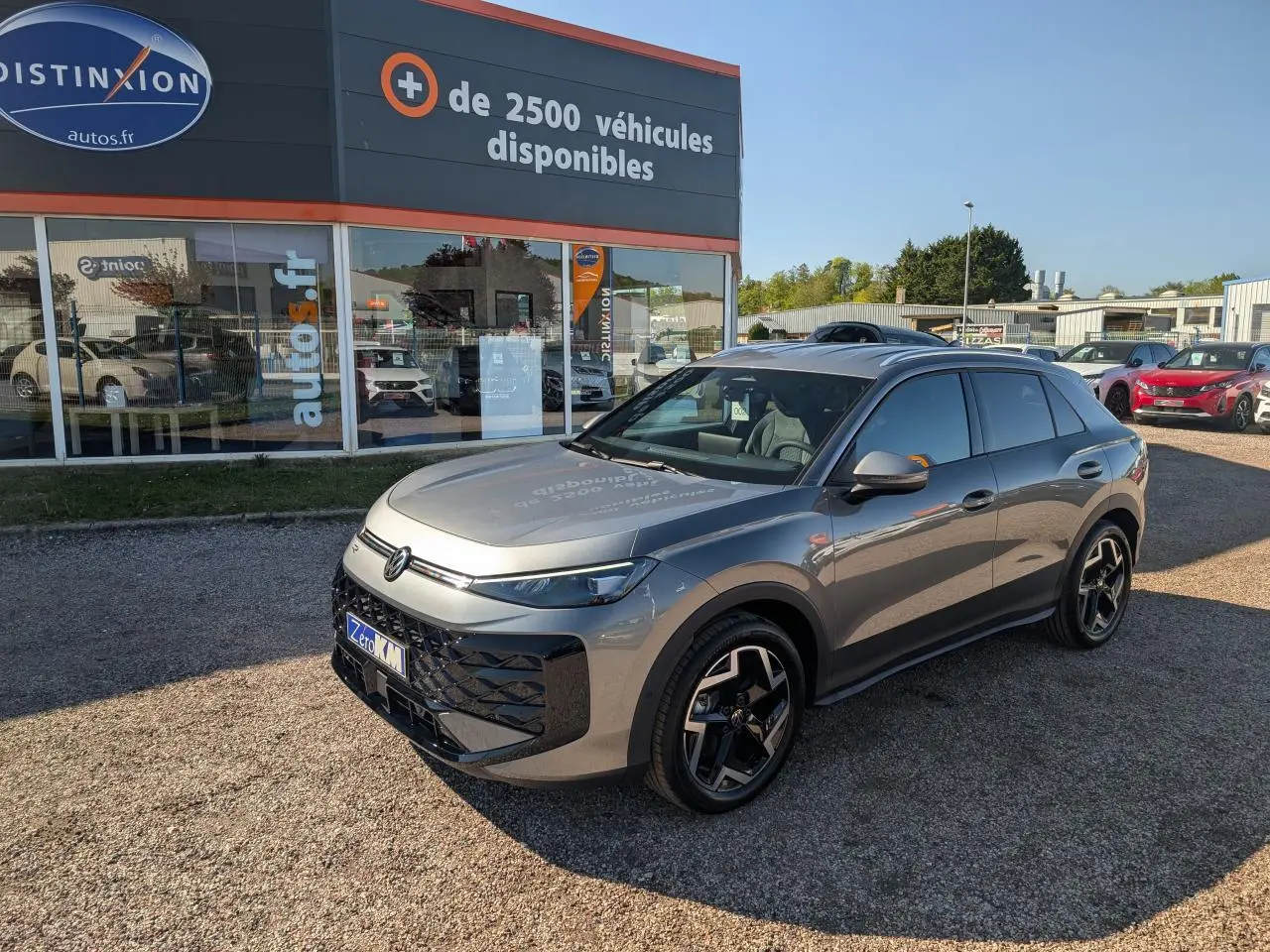 Volkswagen T-Roc gris métallisé vu en 3/4 avant droit, avec jantes 18 pouces et toit noir.