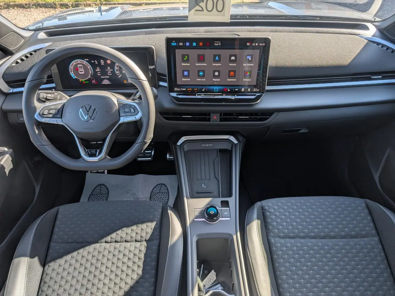 Vue intérieure avant du Volkswagen T-Roc 2026 avec tableau de bord numérique et écran tactile central, sièges tissu R-Line gris.