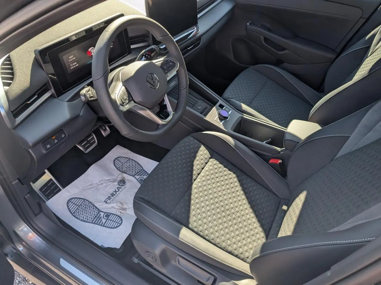 Vue intérieure côté conducteur du Volkswagen T-Roc 2026, sièges tissu R-Line noirs avec volant multifonction cuir.