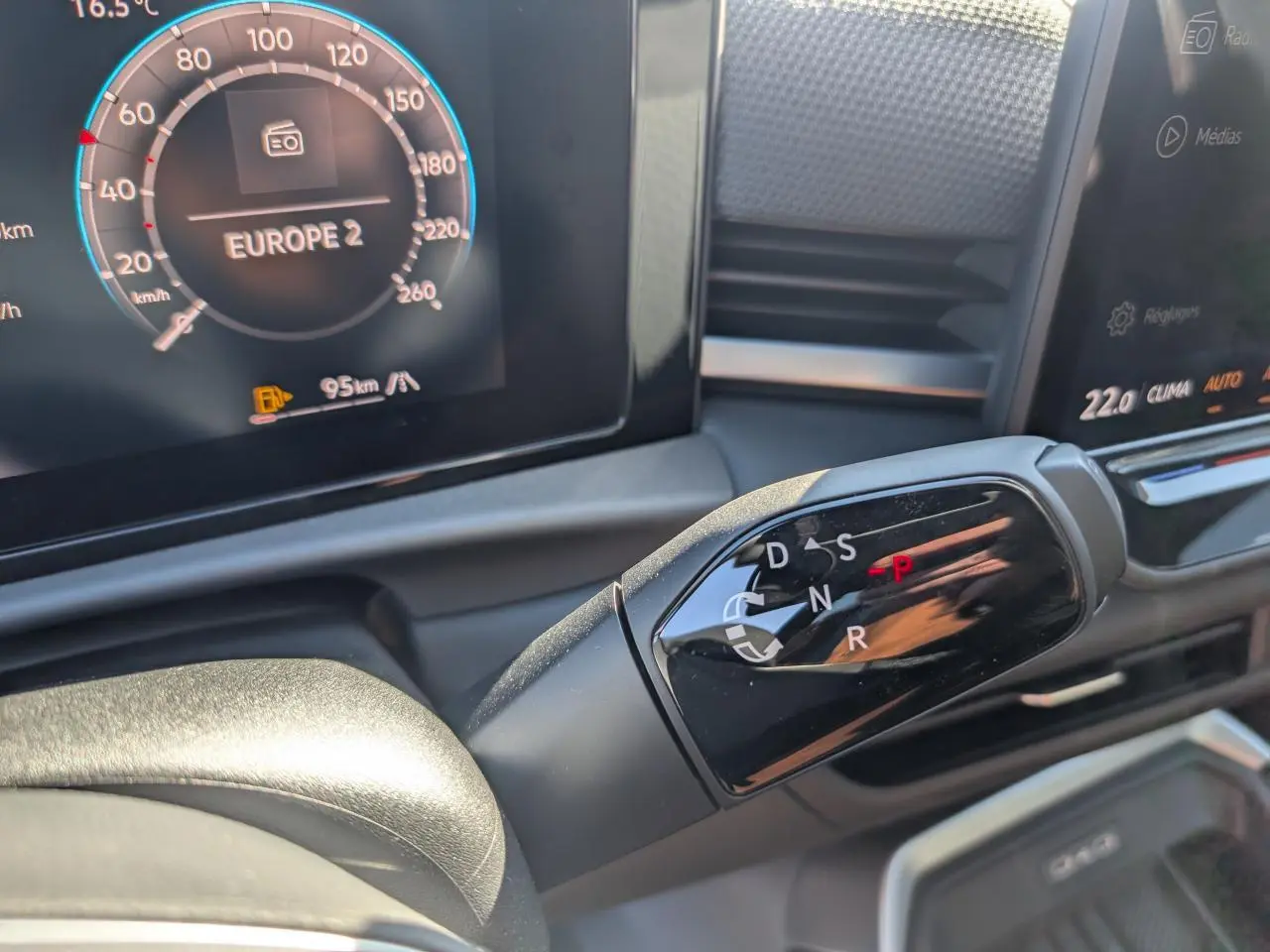 Gros plan sur la commande de boîte automatique DSG 7 du Volkswagen T-Roc gris, avec tableau de bord digital en arrière-plan.