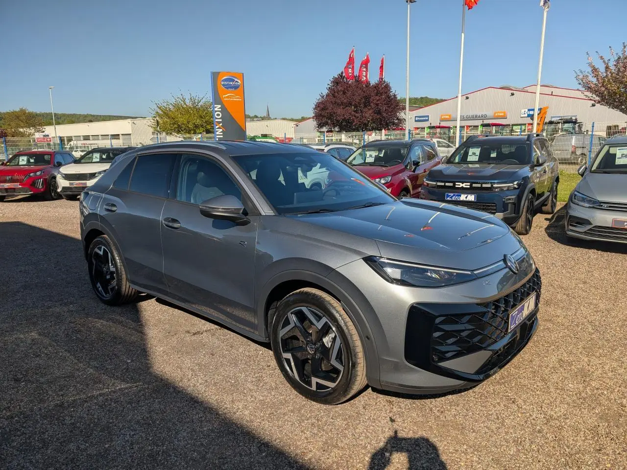 Volkswagen T-Roc gris métallisé en 3/4 avant droit avec jantes noires et calandre R-Line distinctive.