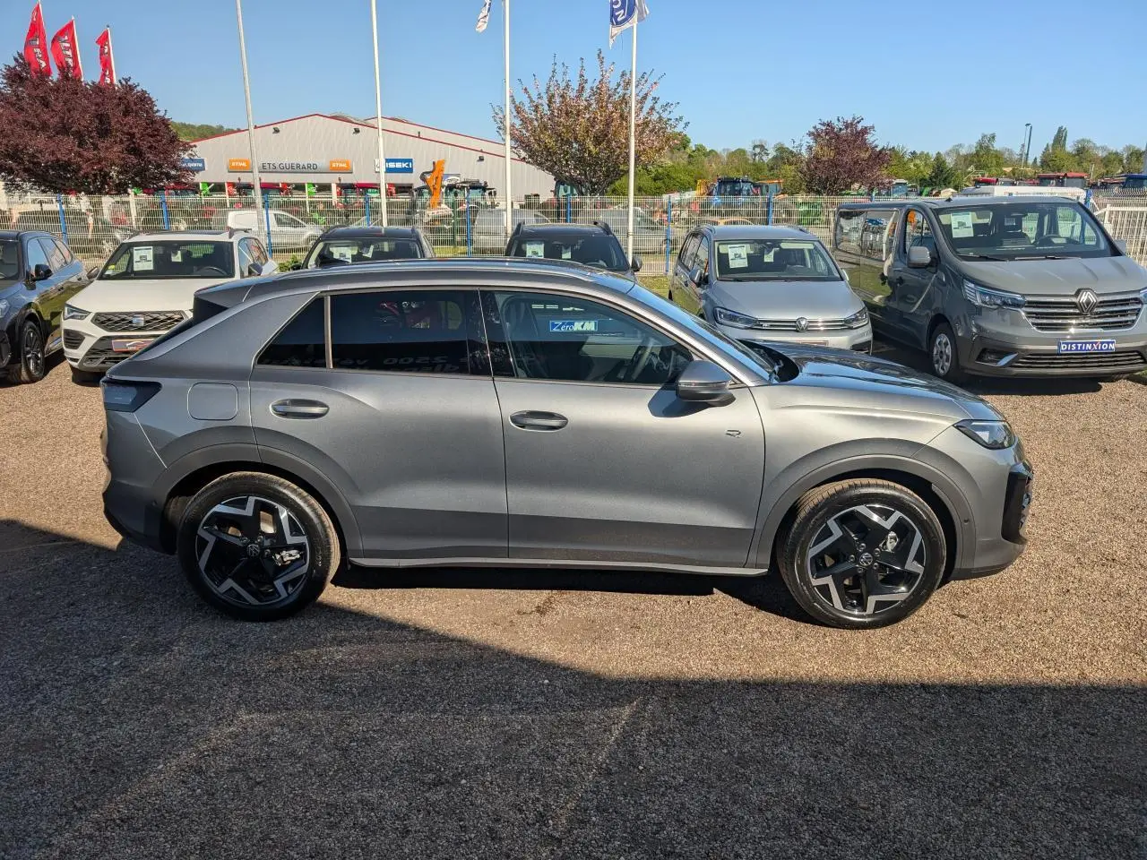 Volkswagen T-Roc gris métallisé vu de profil côté gauche, avec jantes noires et vitres surteintées.