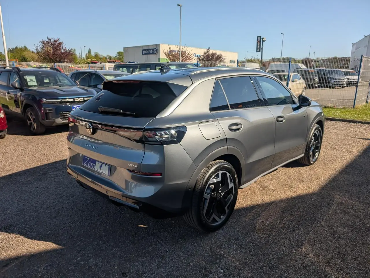 Vue 3/4 arrière droite d'un Volkswagen T-Roc gris métallisé avec jantes noires et vitres arrière surteintées.