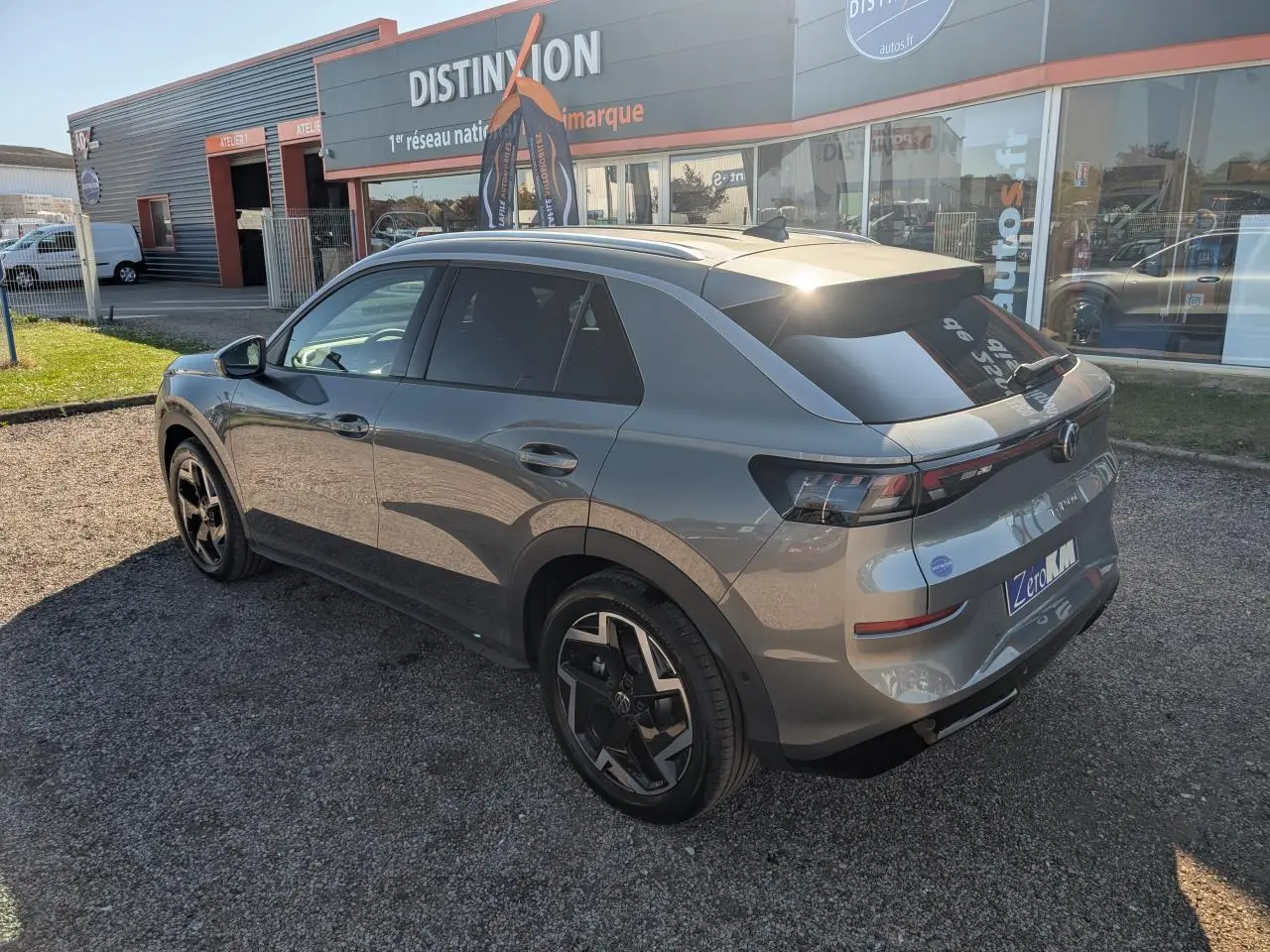 Volkswagen T-Roc gris métallisé vu en 3/4 arrière droit, avec jantes noires et vitres arrière surteintées.