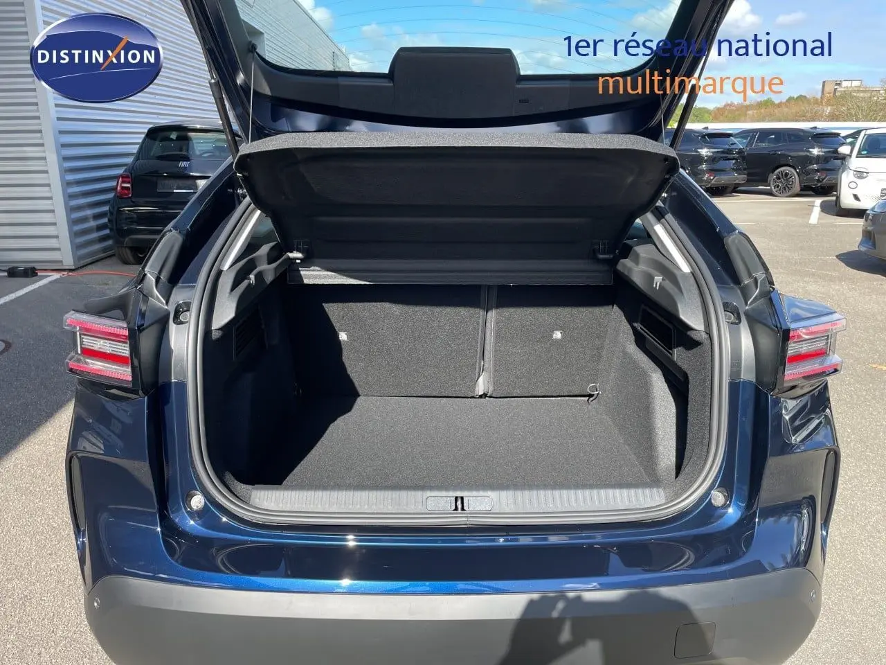 Coffre ouvert vu de l'arrière d'une Citroën C4 Hybrid 145ch bleu eclipse métal, avec hayon relevé en extérieur.