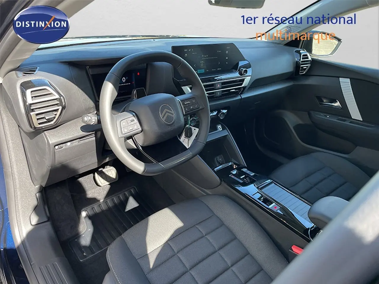 Vue intérieure côté conducteur de la Citroën C4 Hybrid 2026, avec tableau de bord moderne et sièges tissu gris.