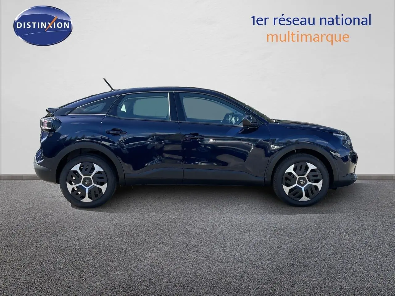 Profil droit d'une Citroën C4 Hybrid 145ch bleu éclipse métal avec jantes distinctives, sur fond neutre intérieur showroom.