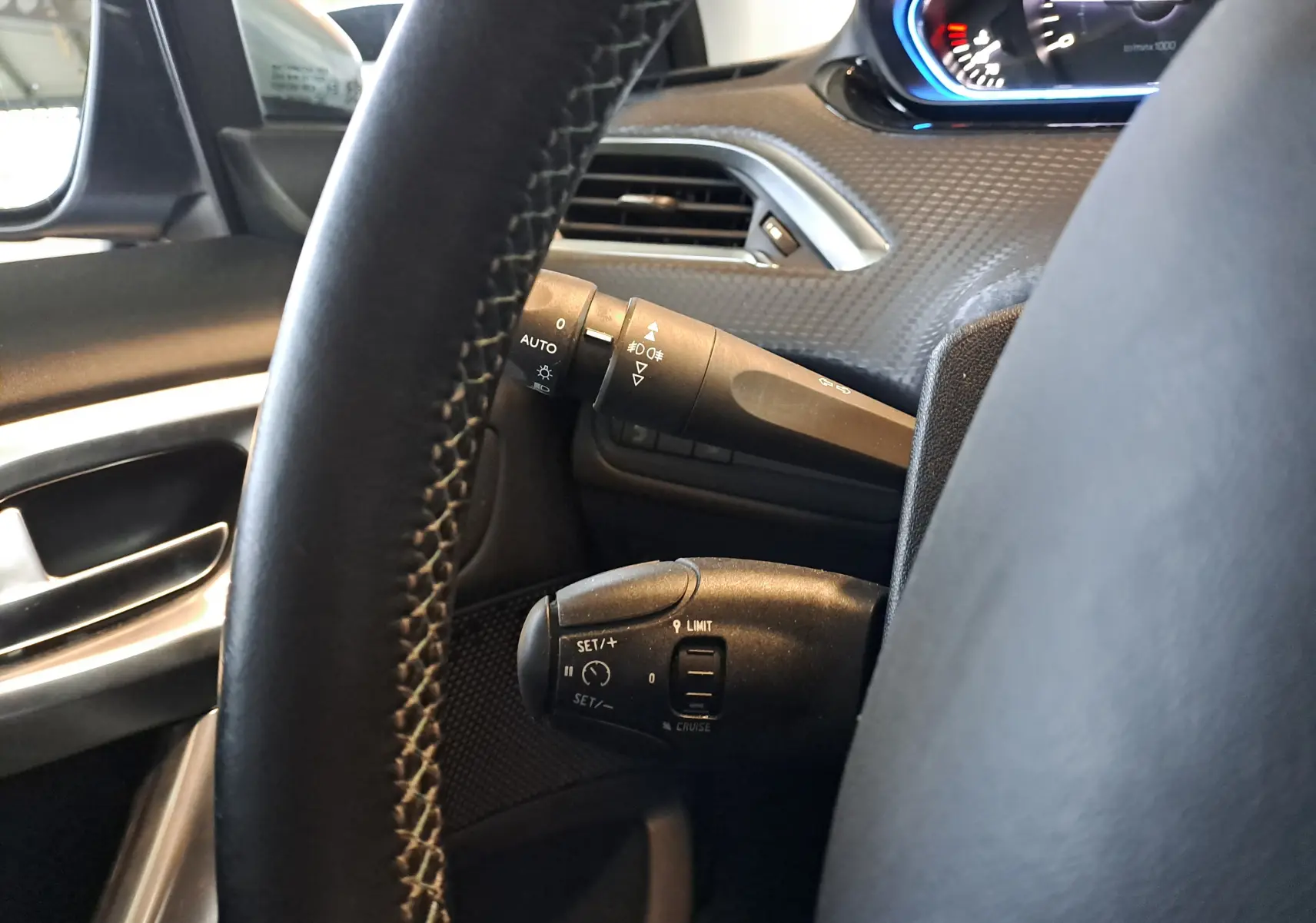 Détail du volant noir et des commandes de régulateur de vitesse dans l'habitacle gris d'une Peugeot 2008 2019.