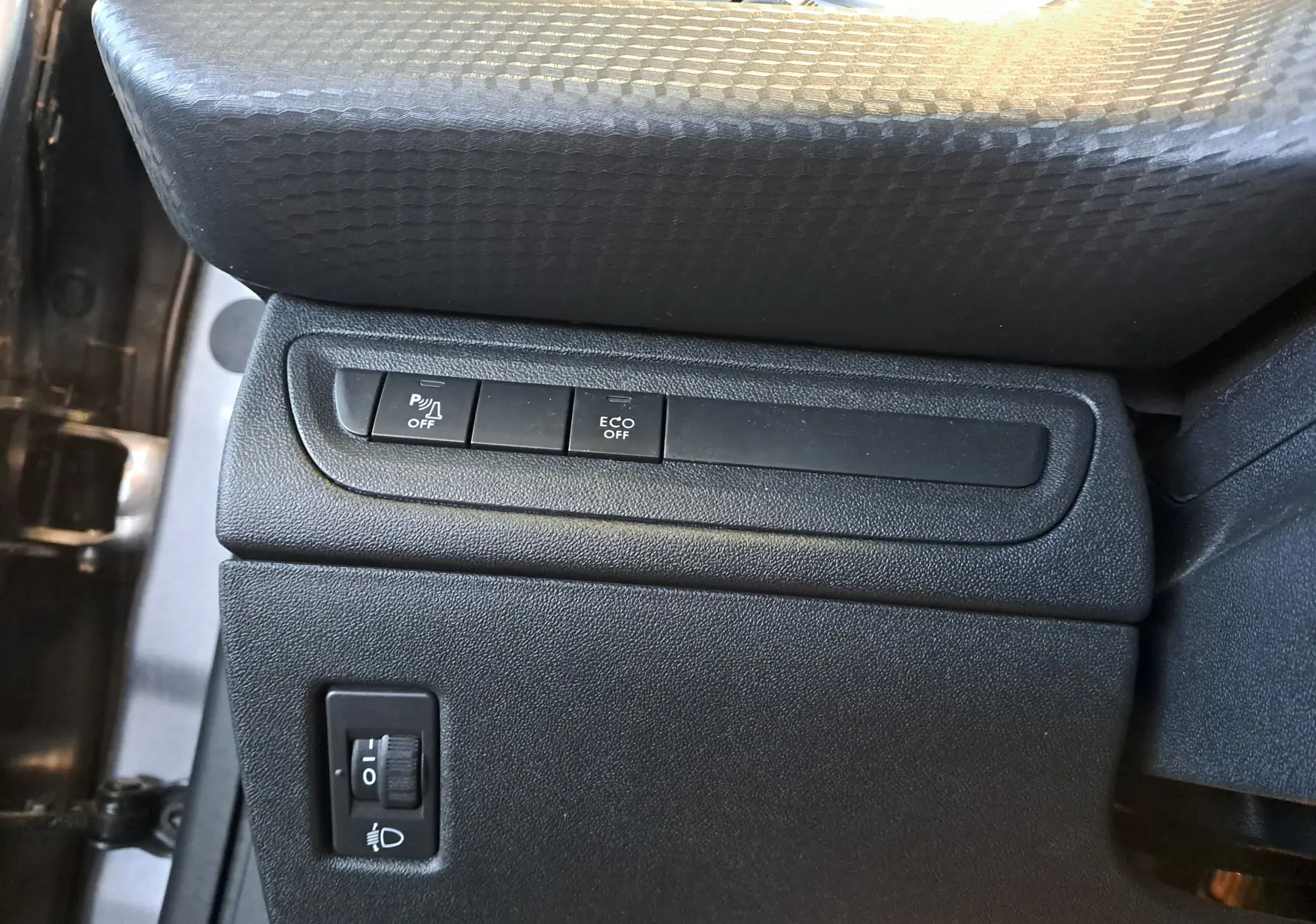 Gros plan sur les commandes de la console côté conducteur du Peugeot 2008 gris, avec boutons de désactivation parking et mode Eco.