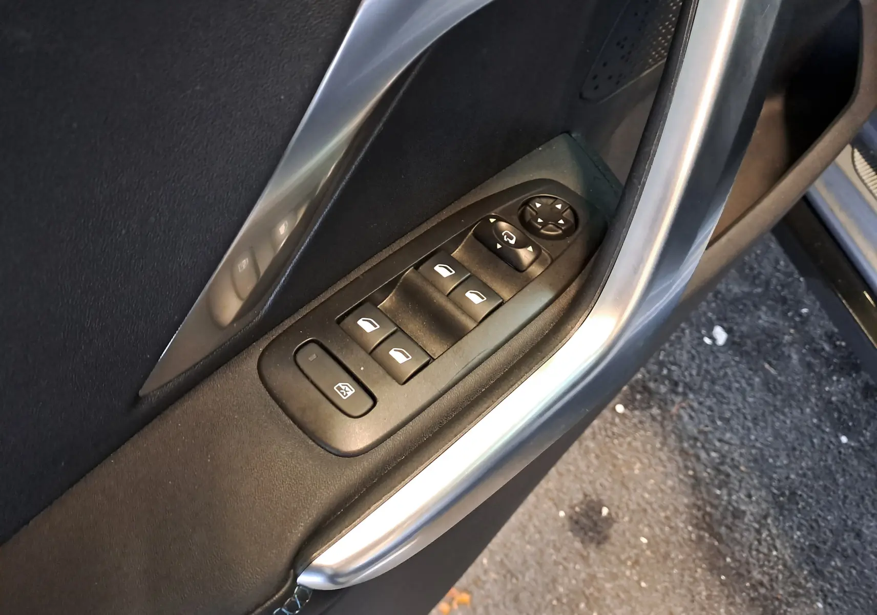Vue rapprochée des commandes de lève-vitres sur la porte côté gauche d'une Peugeot 2008 gris 2019.