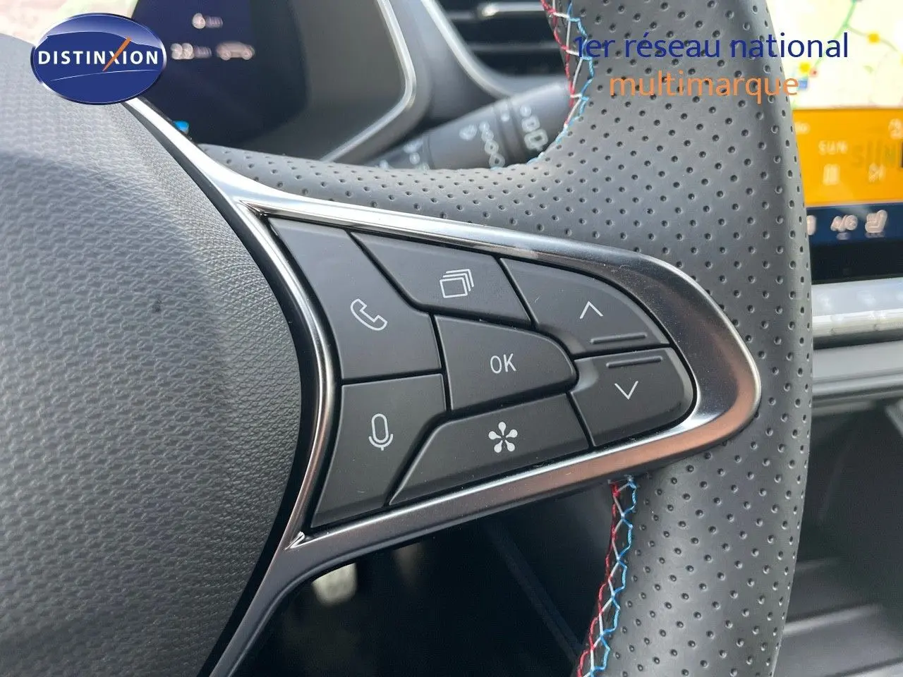 Gros plan sur les commandes du volant perforé avec surpiqûres tricolores du Renault Symbioz gris Rafale 2024.
