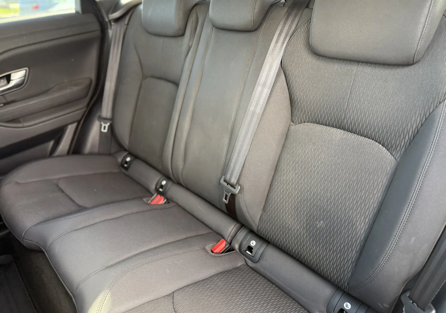 Vue intérieure sur les sièges arrière gris foncé du Range Rover Evoque 2017, montrant les ceintures et fixations ISOFIX.