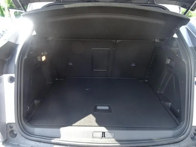 Coffre ouvert en vue arrière d'un Peugeot 3008 gris clair, montrant un espace de chargement propre et spacieux.