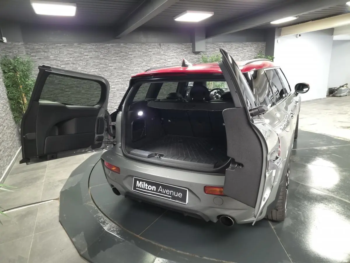 Vue arrière ouverte d'une MINI Clubman gris métallisé avec portes de coffre papillon dans un garage.