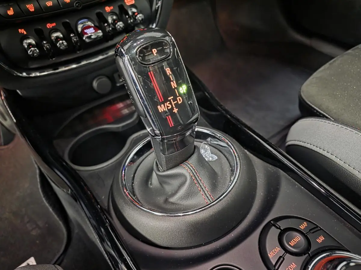 Le levier de vitesses automatique noir avec surpiqûres rouges dans l'habitacle d'une MINI Clubman John Cooper Works.