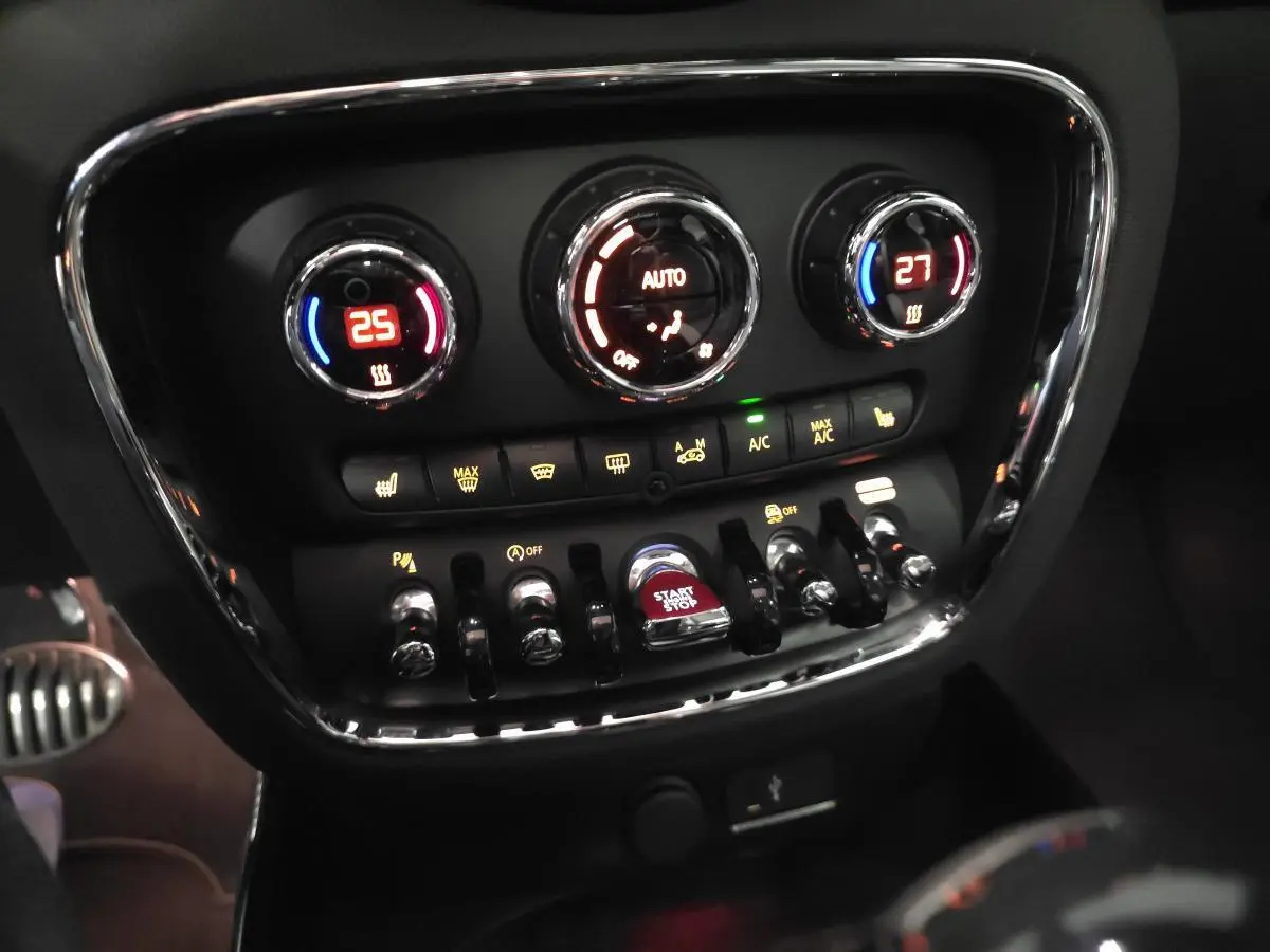 Gros plan sur la console centrale de la MINI Clubman John Cooper Works 2020, avec commandes climatisation bi-zone et bouton start/stop rouge.