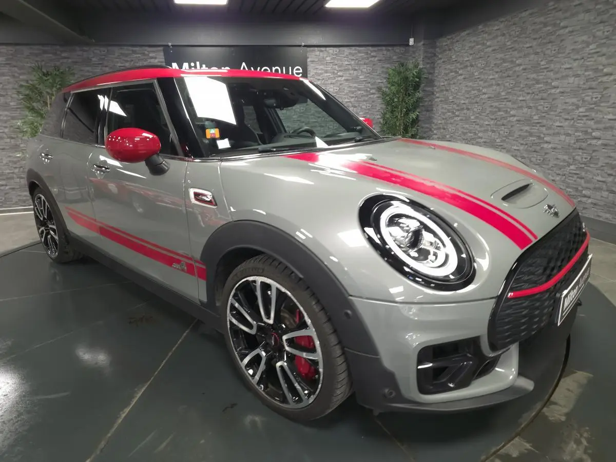 MINI Clubman John Cooper Works gris avec bandes rouges, vue 3/4 avant mettant en valeur jantes et toit rouge.